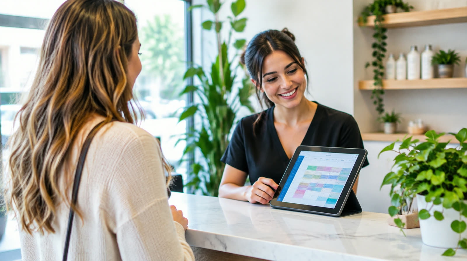 A salon receptionist checking in a customer, with a weekly calendar on a tablet